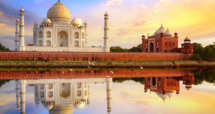 Le Taj Mahal emblématique et la mosquée au coucher de soleil éclatant parfaitement reflétés dans le fleuve Yamuna.
