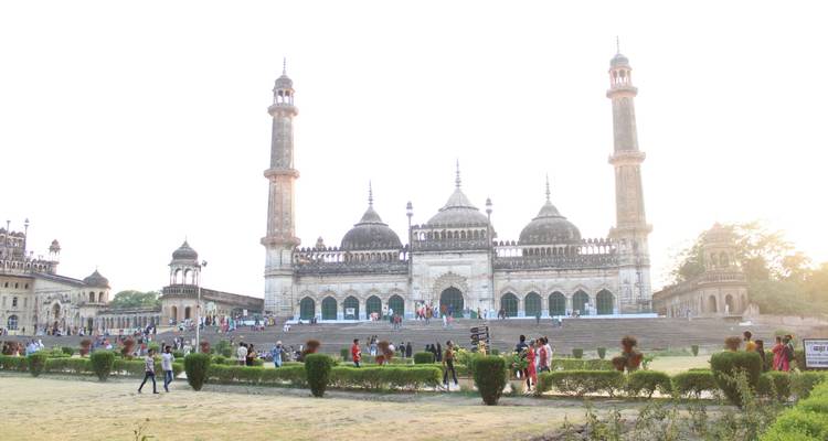 Majestic Mughal-era mosque complex with twin minarets and tourists strolling its vast courtyard.