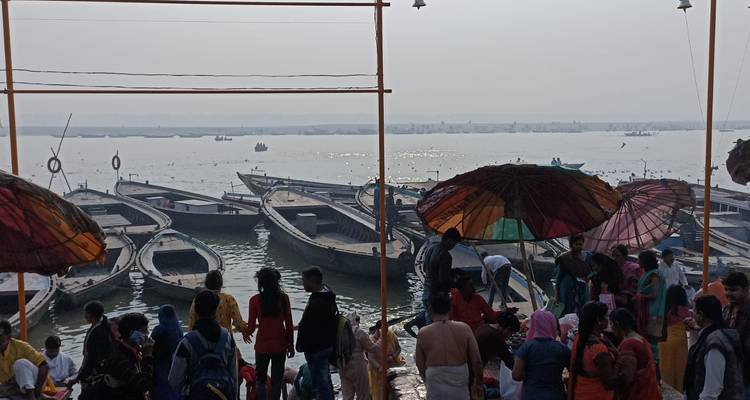 Drukke rivieroever met boten en mensen.