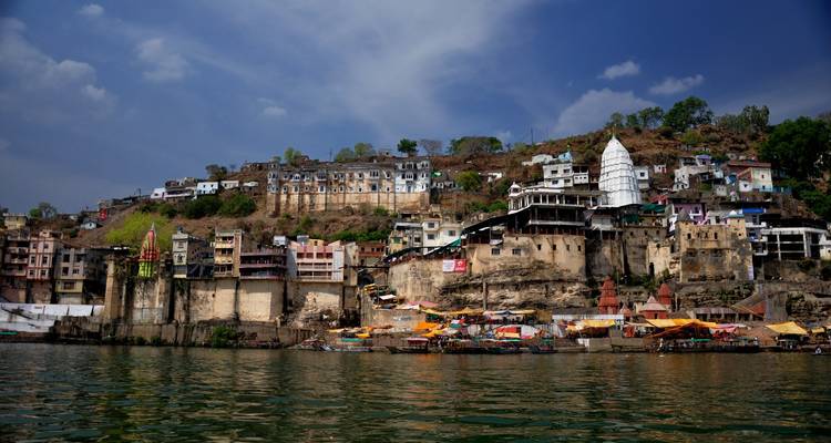 Vue sur Maheshwar depuis la rivière avec temples et bâtiments.