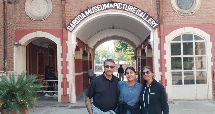 Drie personen die poseren voor de ingang van een museum.