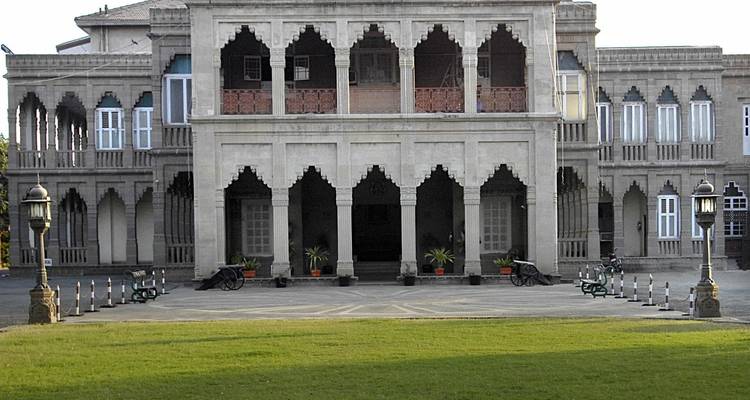 Historisch gebouw met bogen en een grasveld ervoor.