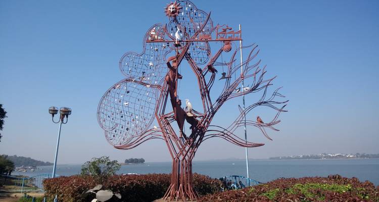 Gebeeldhouwde boom met decoratieve elementen bij het meer.