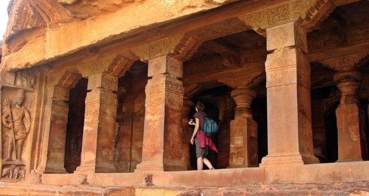 A person exploring ancient stone columns and carvings.