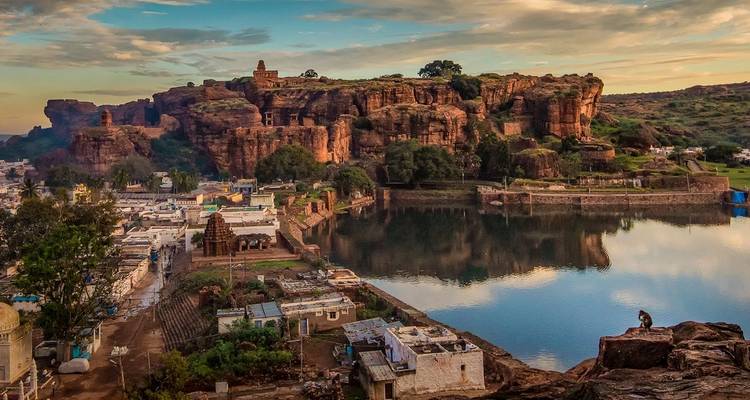 Scenic view of ancient structures and water reflecting the cliffs.