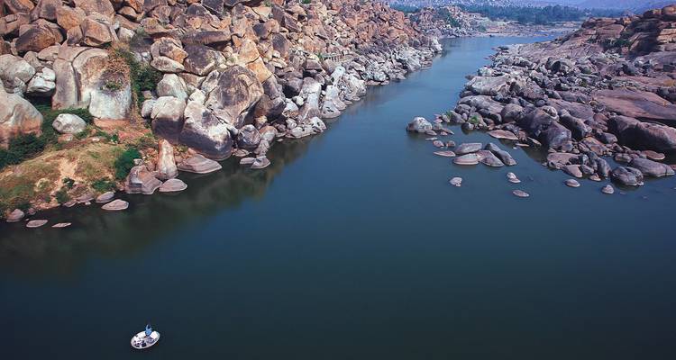Ein sich schlängelnder Fluss durch felsiges Gelände mit einem einsamen Boot.