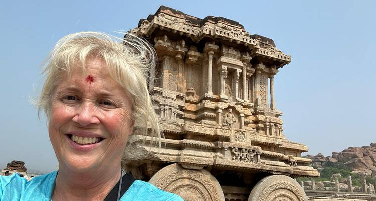 A smiling person in front of the Stone Chariot in Hampi.