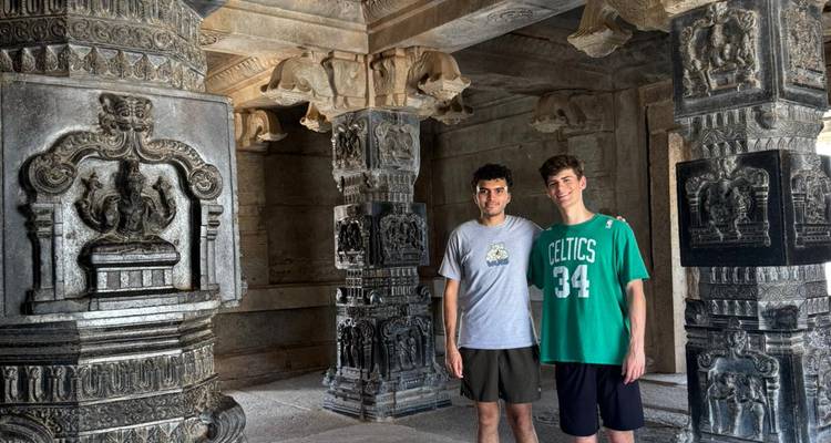 Two people standing inside a temple with ornate stone pillars.