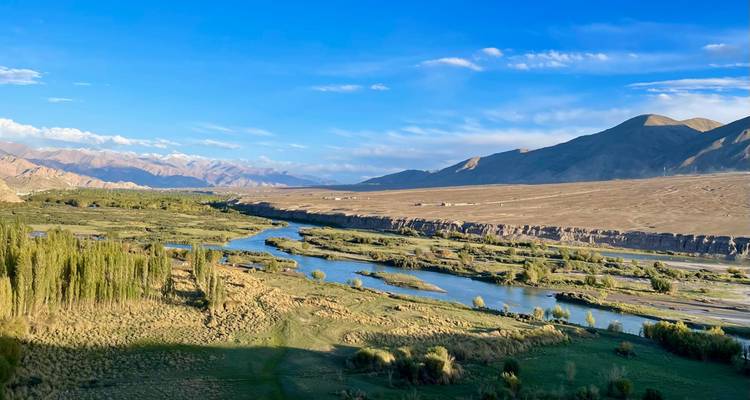 Fluss, der sich durch ein üppiges Tal mit Bergen im Hintergrund windet