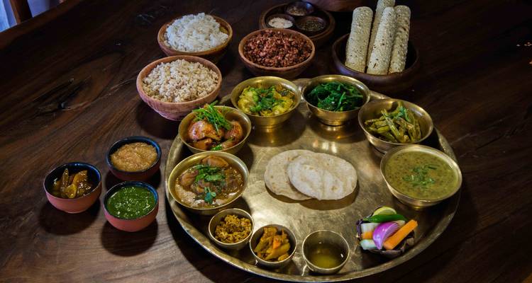 Festín tradicional nepalí servido en un thali de latón con curries, arroz, dal, chutneys y pan sin levadura.