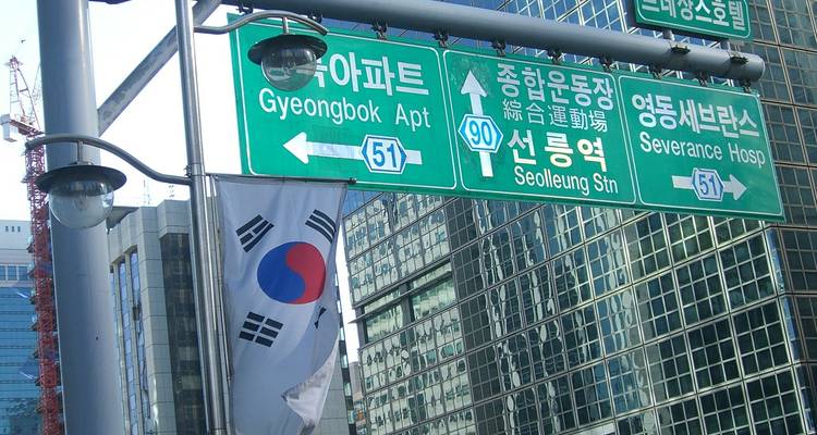 Street signs and a South Korean flag in an urban setting.