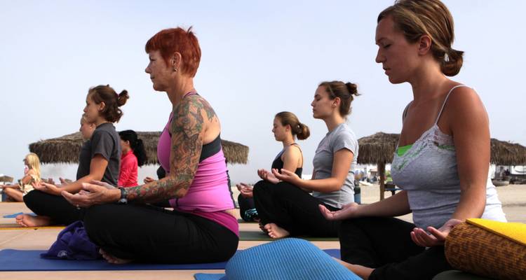 Gruppe von Menschen, die draußen auf Yogamatten meditieren.