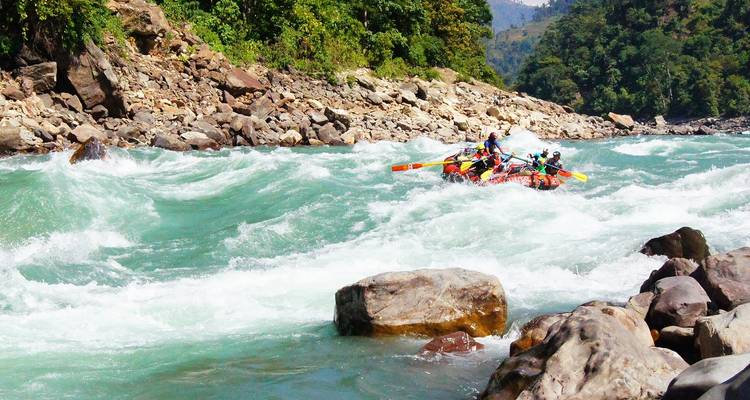 A raft on a river surrounded by rocky landscape and green hills.