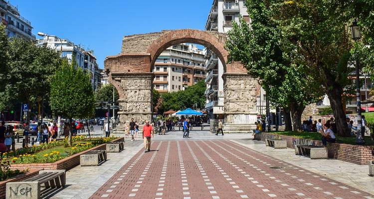 Gewelfde oude poort in een stadsomgeving met mensen die voorbijlopen.