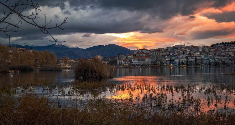 Stadsskyline bij zonsondergang weerspiegeld in een meer.