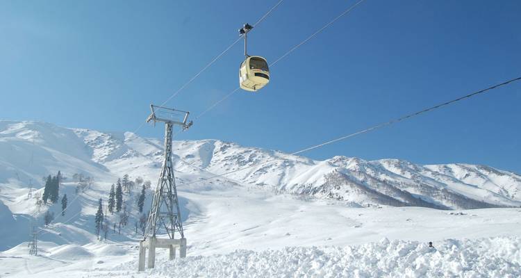 Gondelbahn mit schneebedeckten Bergen im Hintergrund.