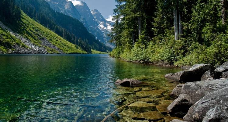 Klarer See mit Bergen und Wald.