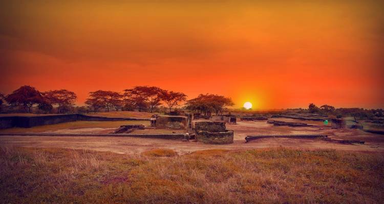 Sunset over ruins with vibrant orange skies.