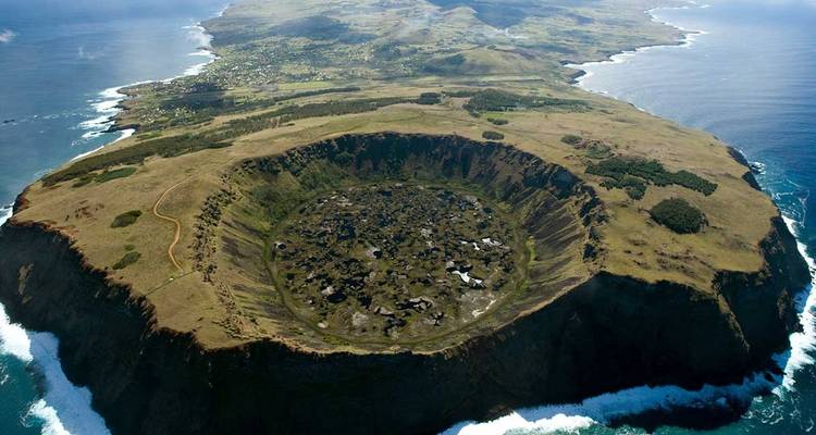 Aerial view of a volcanic crater on Easter Island surrounded by ocean.