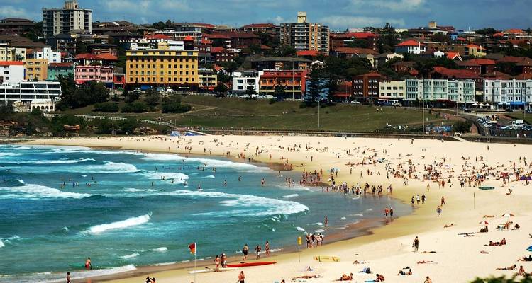 Druk Bondi Beach met mensen die genieten van de zon en golven.