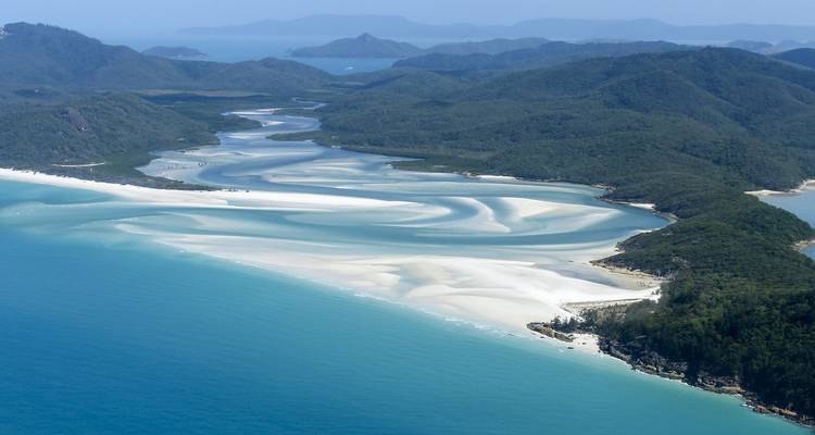 Aerial view of scenic white sand beaches and lush green hills.