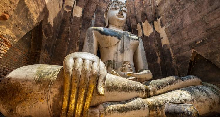 Close-up of colossal seated Buddha within the narrow chamber of an ancient ruin.