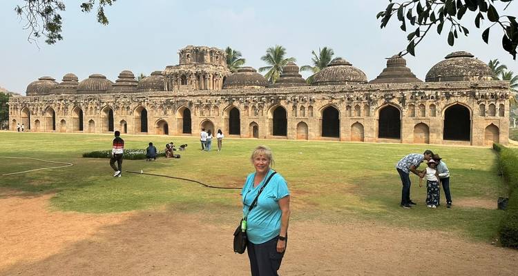 Woman standing on a lawn in front of a long ancient building.