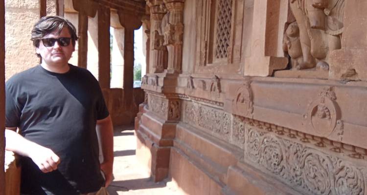 A person standing beside ornately carved temple columns.