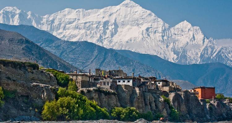 Village on a hill with snowy mountains in the background.