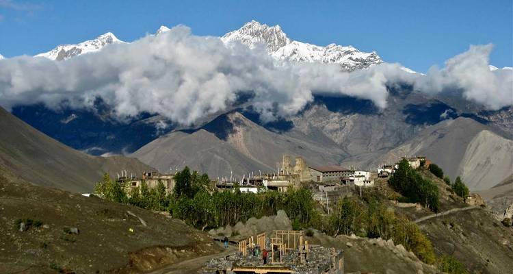 Mountain village with clouds and peaks in the distance.