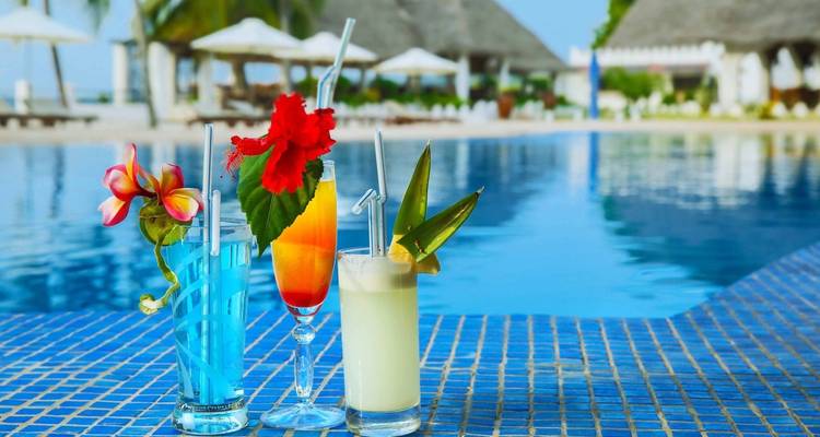 Cocktails by the pool with a beach view in the background.