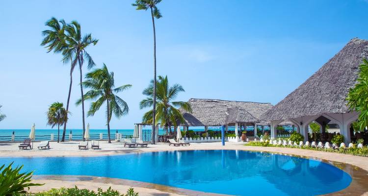 Resort pool near the ocean with palm trees in Zanzibar.