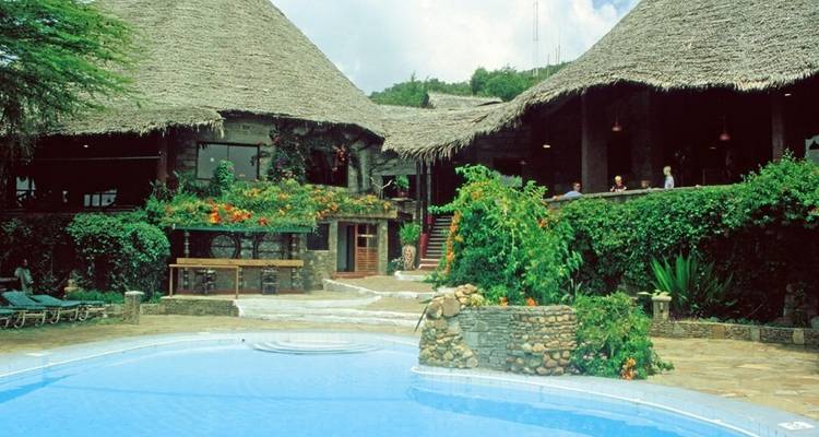 Lodge mit Strohdächern an einem Swimmingpool.