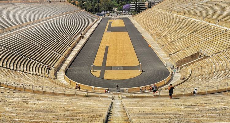 Wide view down the historic Panathenaic Stadium made of marble with a few tourists exploring