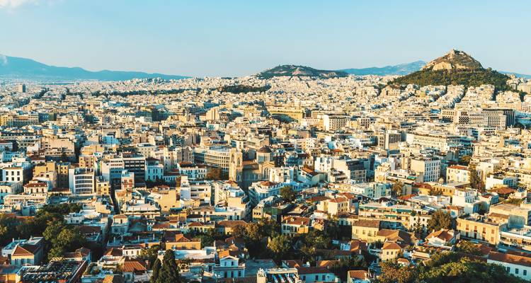 Expansive aerial panorama of Athens urban sprawl with surrounding hills under clear sky