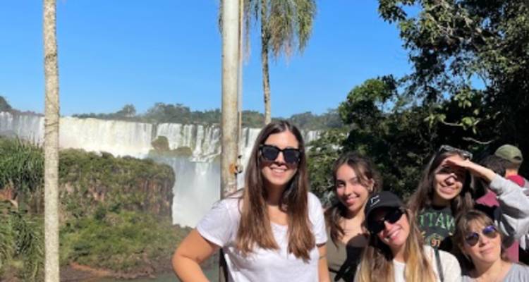 Group of friends posing with a waterfall in the background.