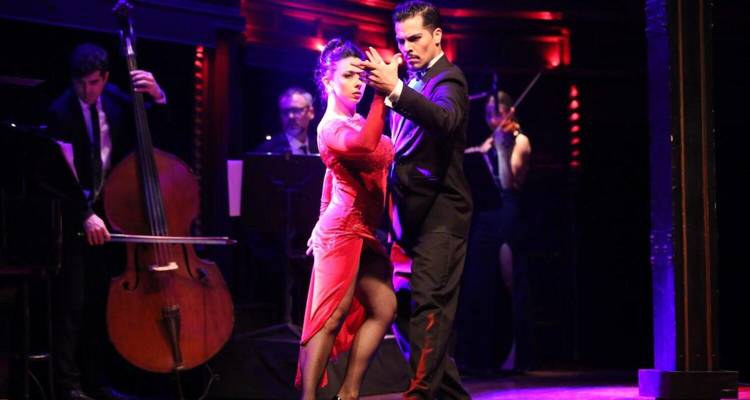 Tango dancers performing on stage with musicians.
