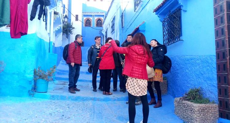 Les visiteurs portant des vestes discutant dans une ruelle d'un bleu éclatant typique de Chefchaouen