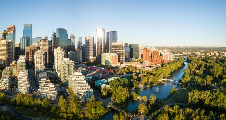 La luz panorámica del amanecer en los rascacielos del centro de Calgary y el sinuoso río Bow rodeado de parques verdes.