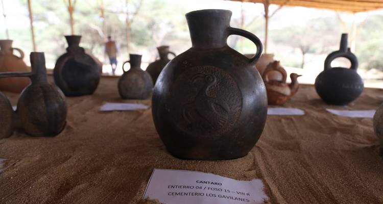 Oude potten tentoongesteld op zand in een archeologische omgeving.