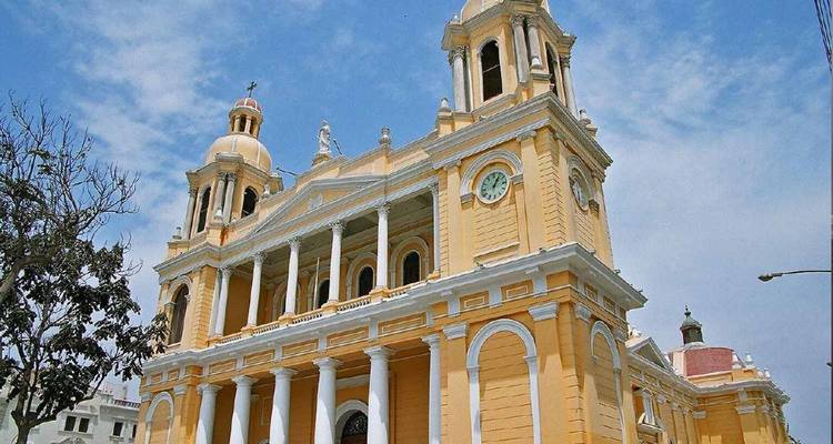 Kathedraal in koloniale stijl met sierlijke gevel en klokkentoren onder een blauwe hemel.
