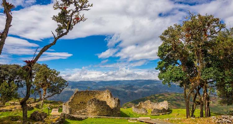 Ruinen umgeben von einer üppigen Landschaft unter blauem Himmel.
