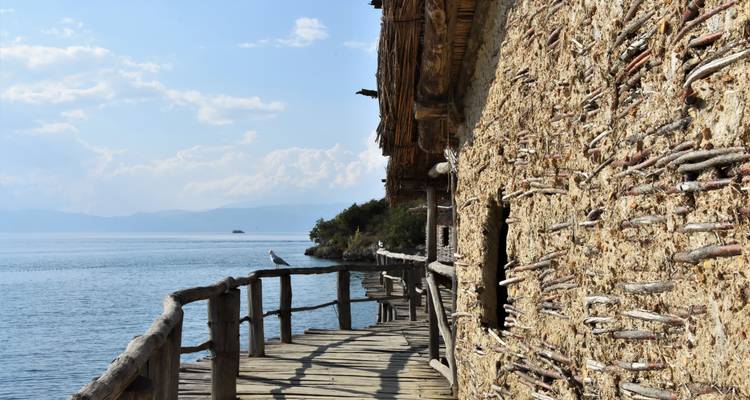 Sentier en bois le long d'un lac serein avec des montagnes au loin.