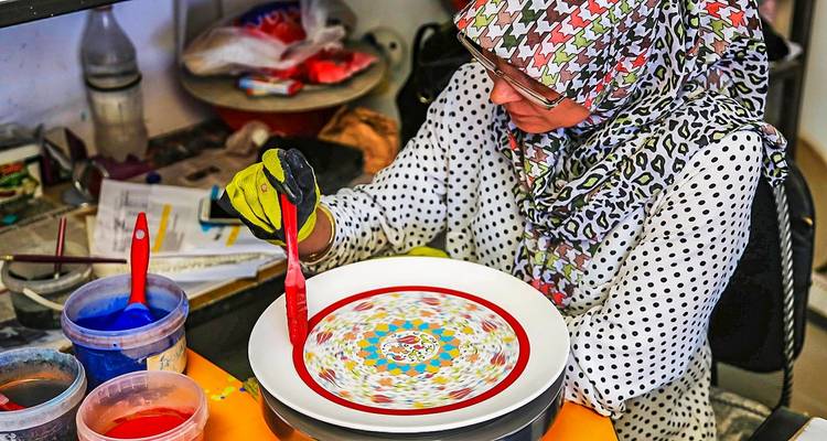 Vrouw die werkt aan kleurrijk keramisch handwerk.