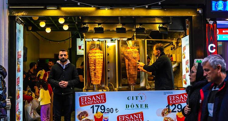 Straatvoedselkraam met mannen die döner kebabs bereiden.