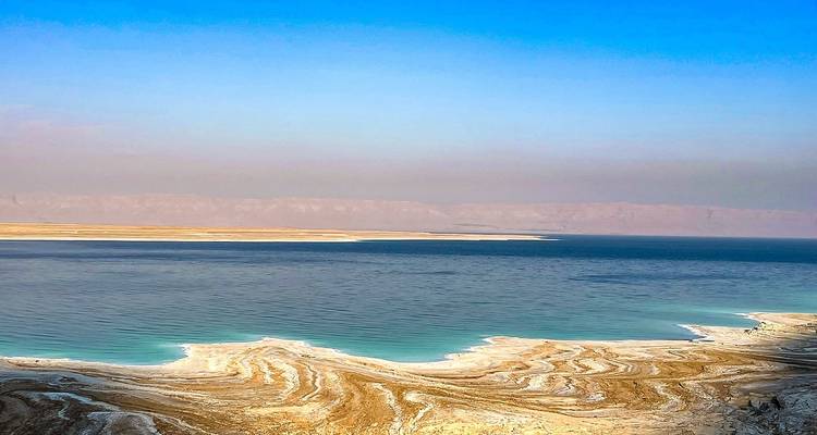 Salzformationen in der Nähe eines großen Gewässers mit fernen Bergen.