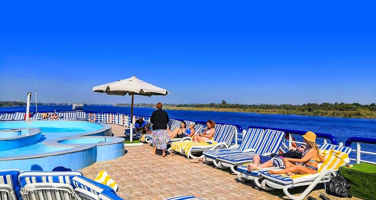 Menschen entspannen auf Liegestühlen am Pool eines Kreuzfahrtschiffs.