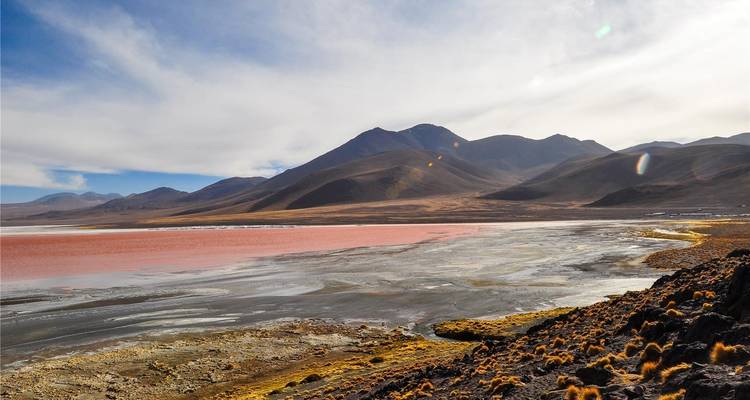 Die atemberaubende, rot gefärbte Laguna Colorada, gerahmt von kahlen Gipfeln unter einem dramatischen Himmel