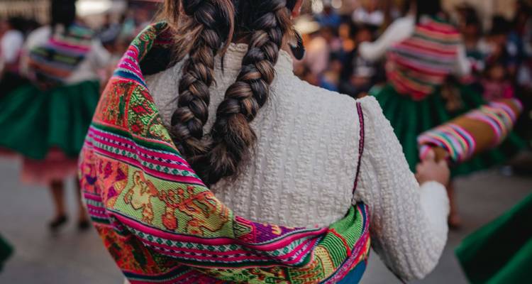 Gros plan sur les cheveux tressés et le châle tissé aux couleurs vives d'une danseuse bolivienne traditionnelle.