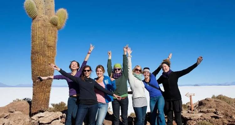 Un grupo de mujeres posando con un cactus grande en el salar.